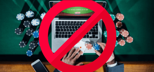hands on laptop with casino chips and a banned icon on top gambling bill